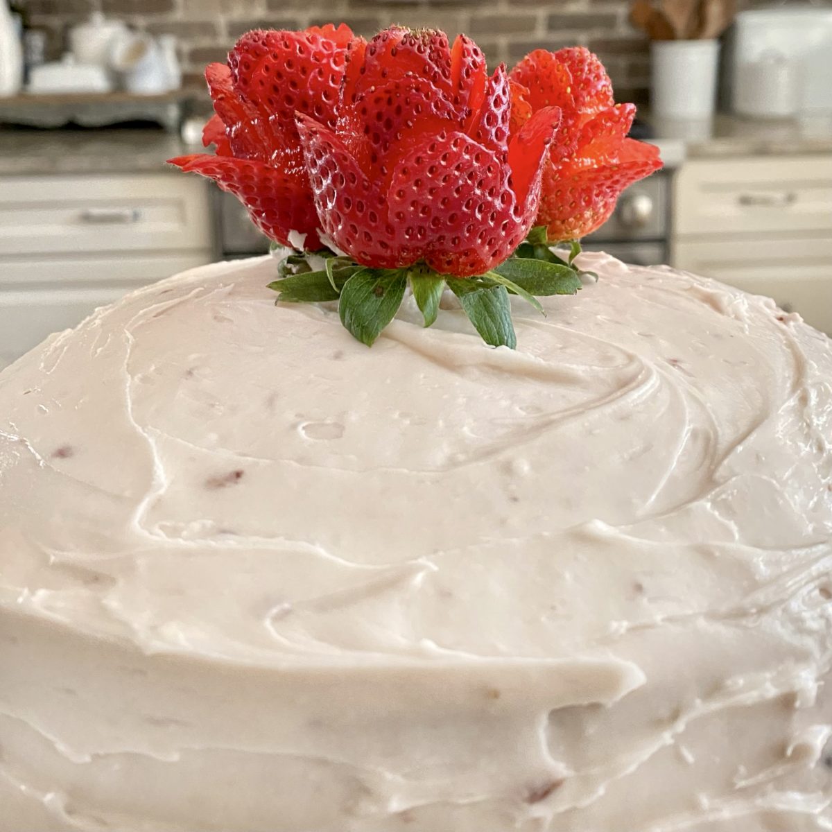 Strawberry roses on top of the cake in the frosting.
