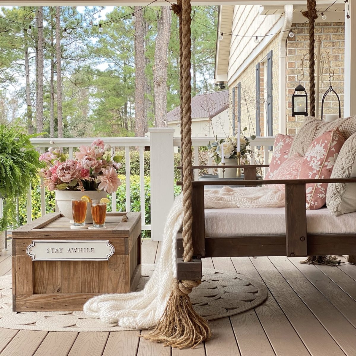 Front porch swing side view with a floral arrangement and iced tea on the coffee table in front of it.