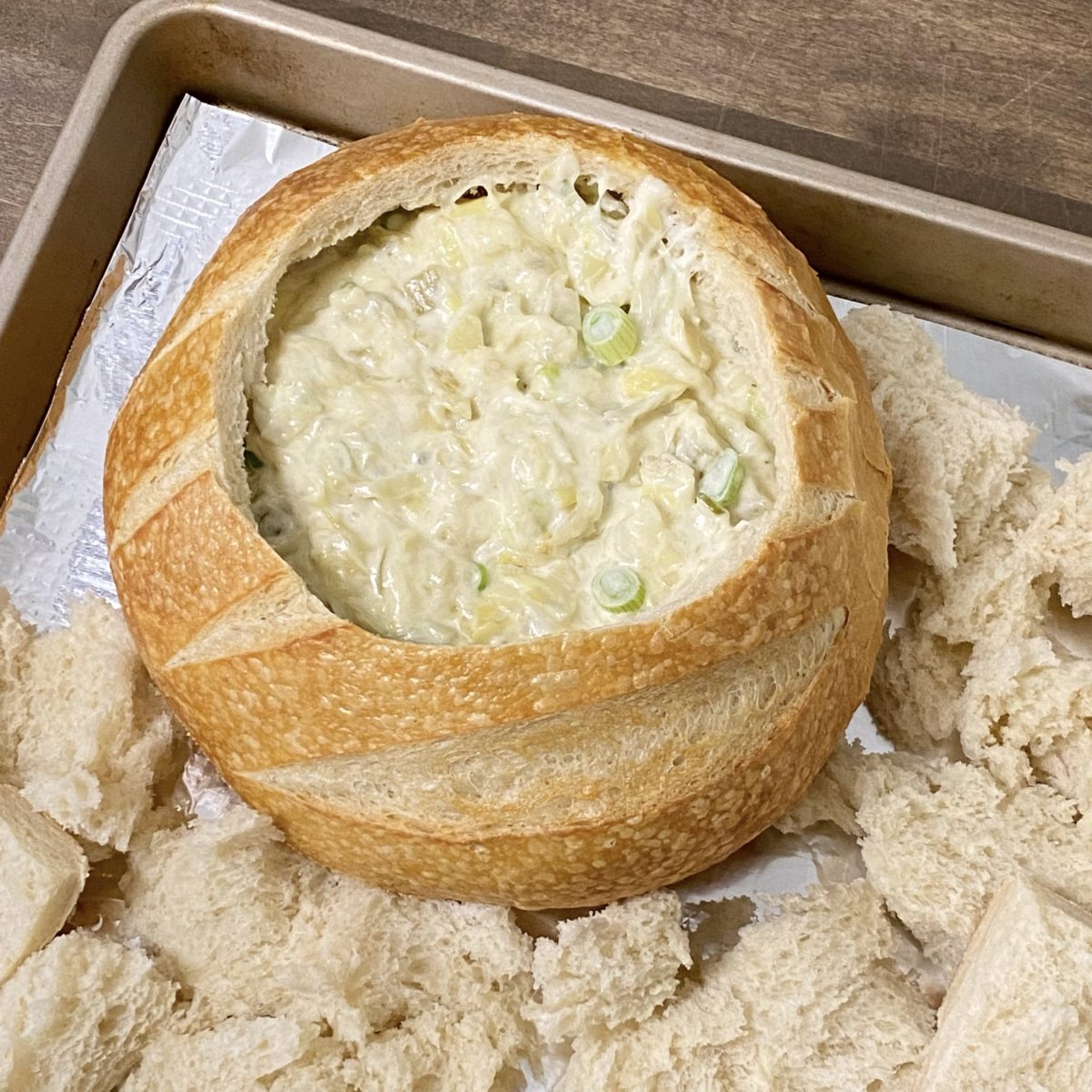 The best artichoke dip in a bread bowl getting ready to bake in the oven.