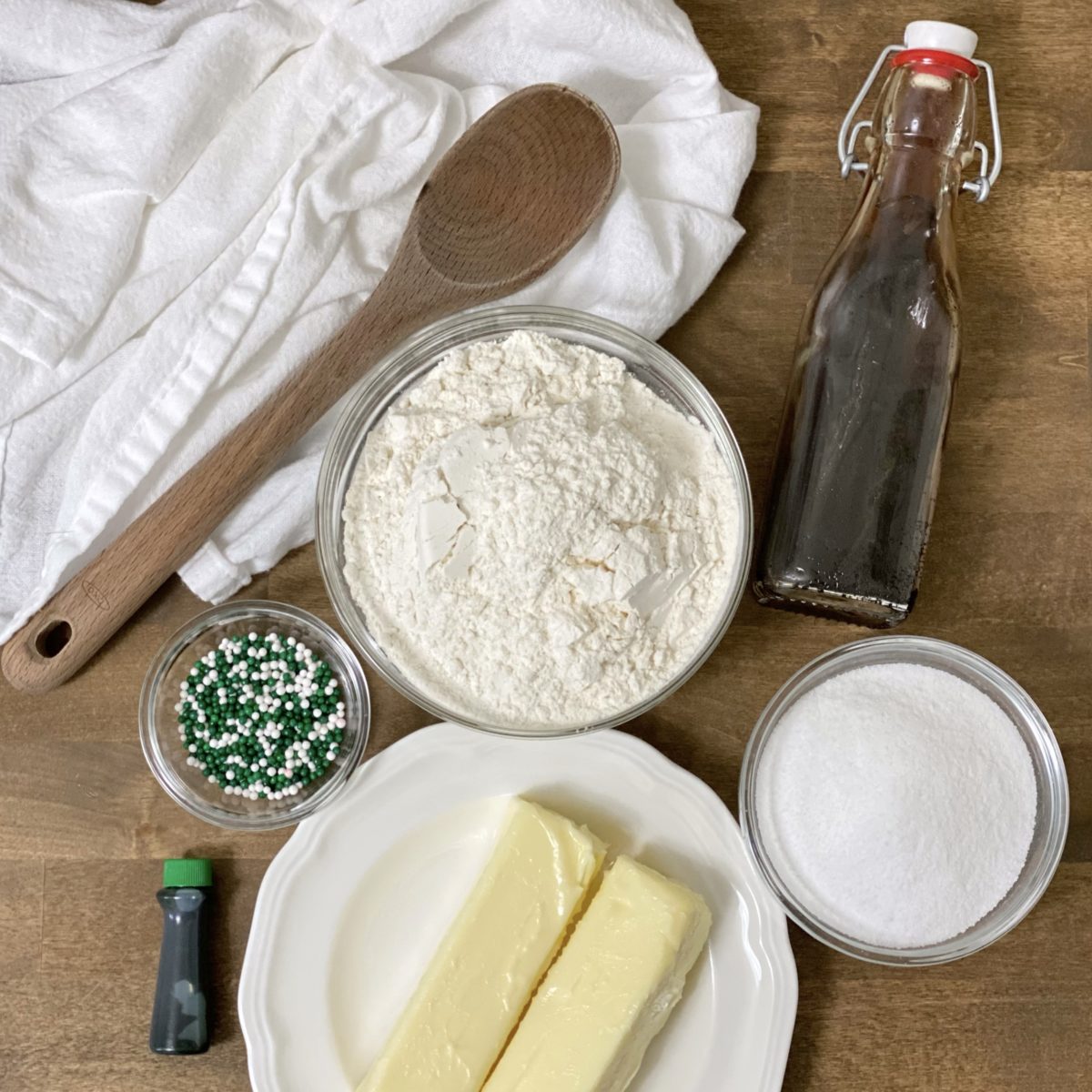 Ingredients for St. Patrick's Day shortbread bites including butter, sugar, flour, vanilla extract, sprinkles and food coloring.
