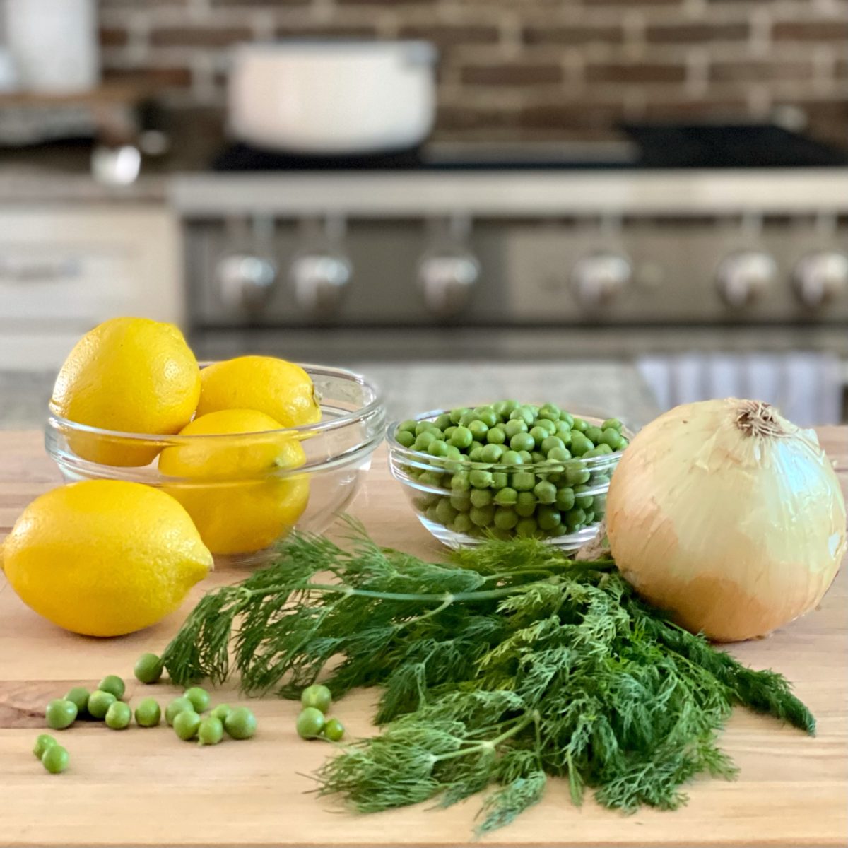 Lemons, peas, onion and fresh dill on a cutting board.