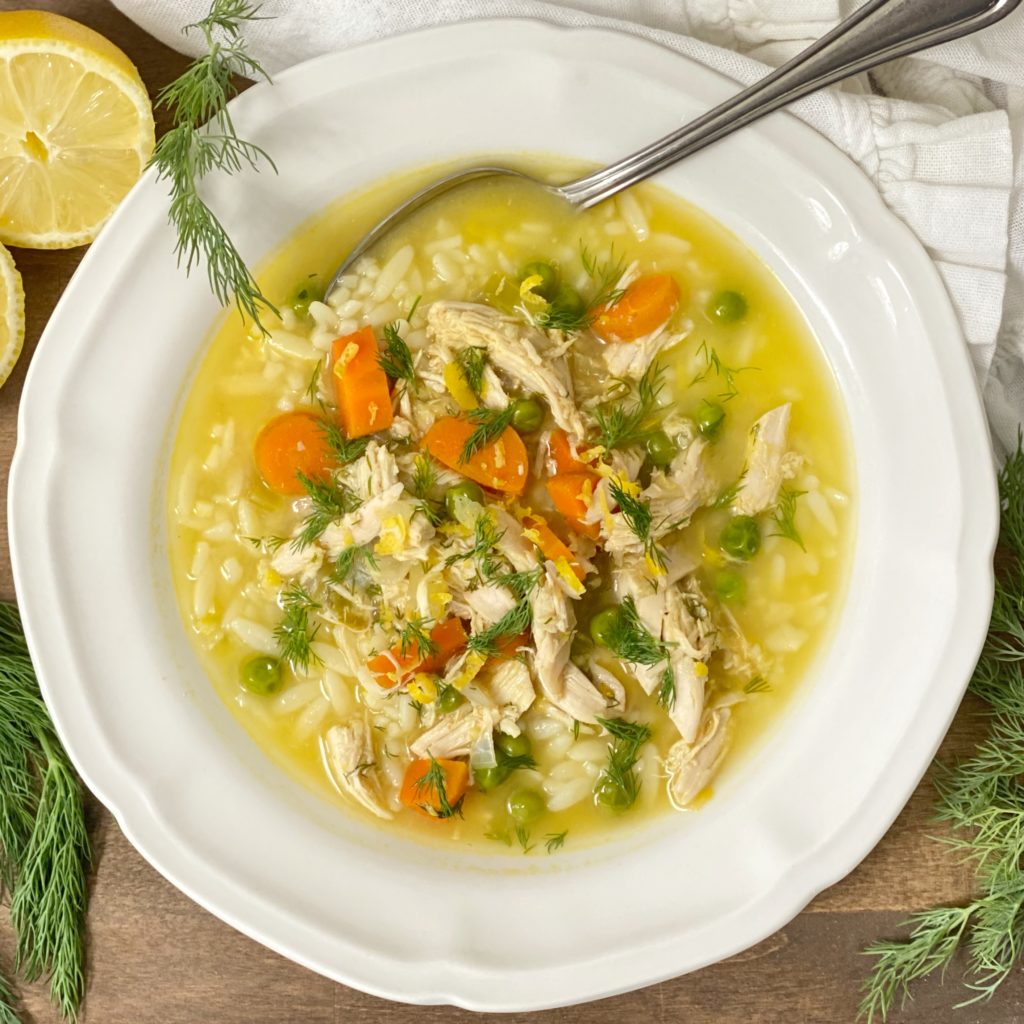 Chicken orzo soup with lemon and dill in a white bowl.