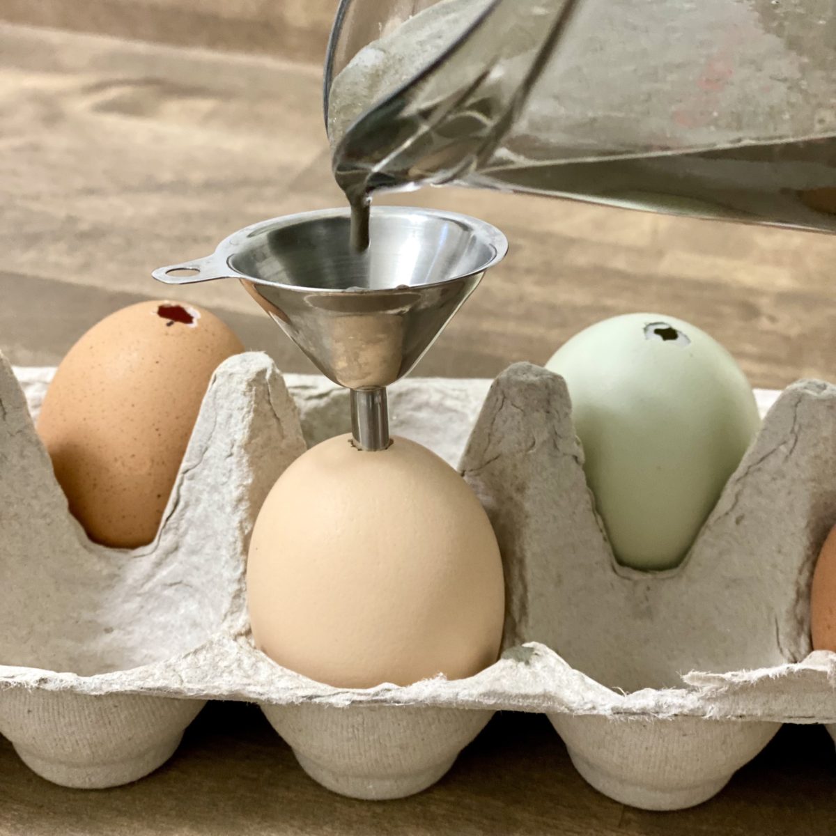 Concrete being poured into a funnel into an egg in a carton.