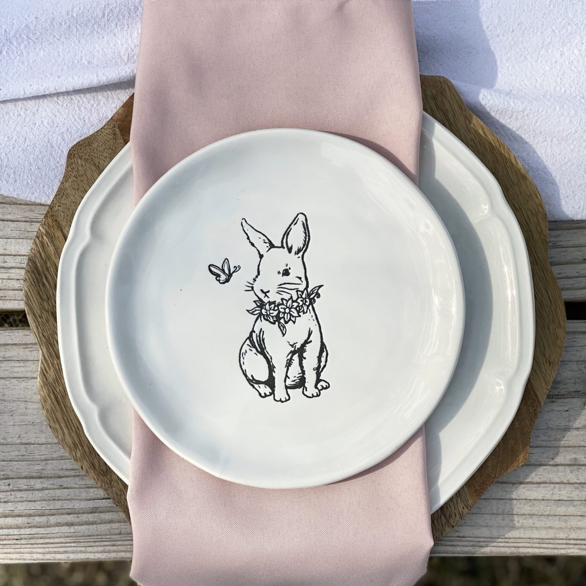 Wood charger, white plate , and a bunny plate set on the table.
