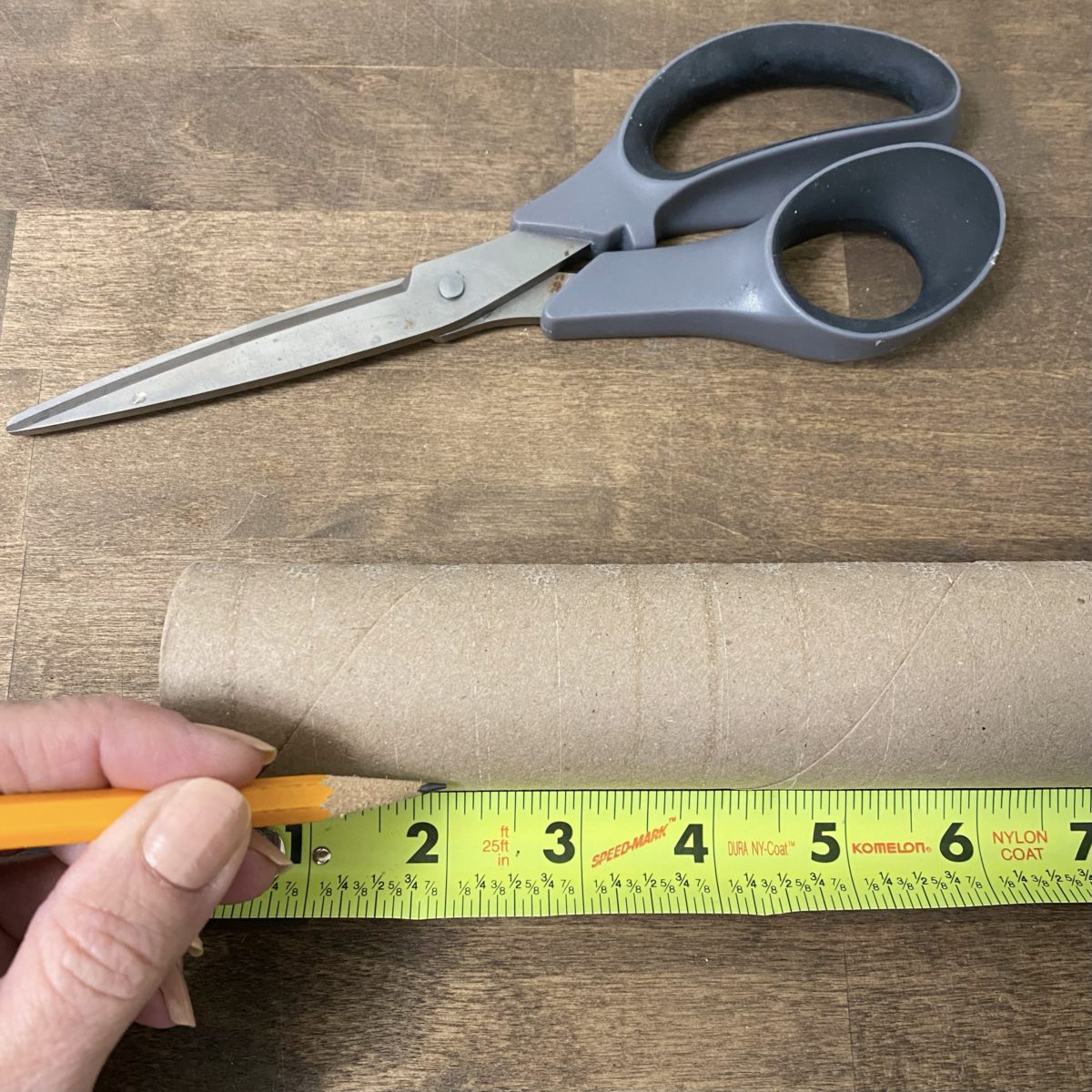 Measuring out 2-inch lengths on the cardboard roll and marking them with a pencil.
