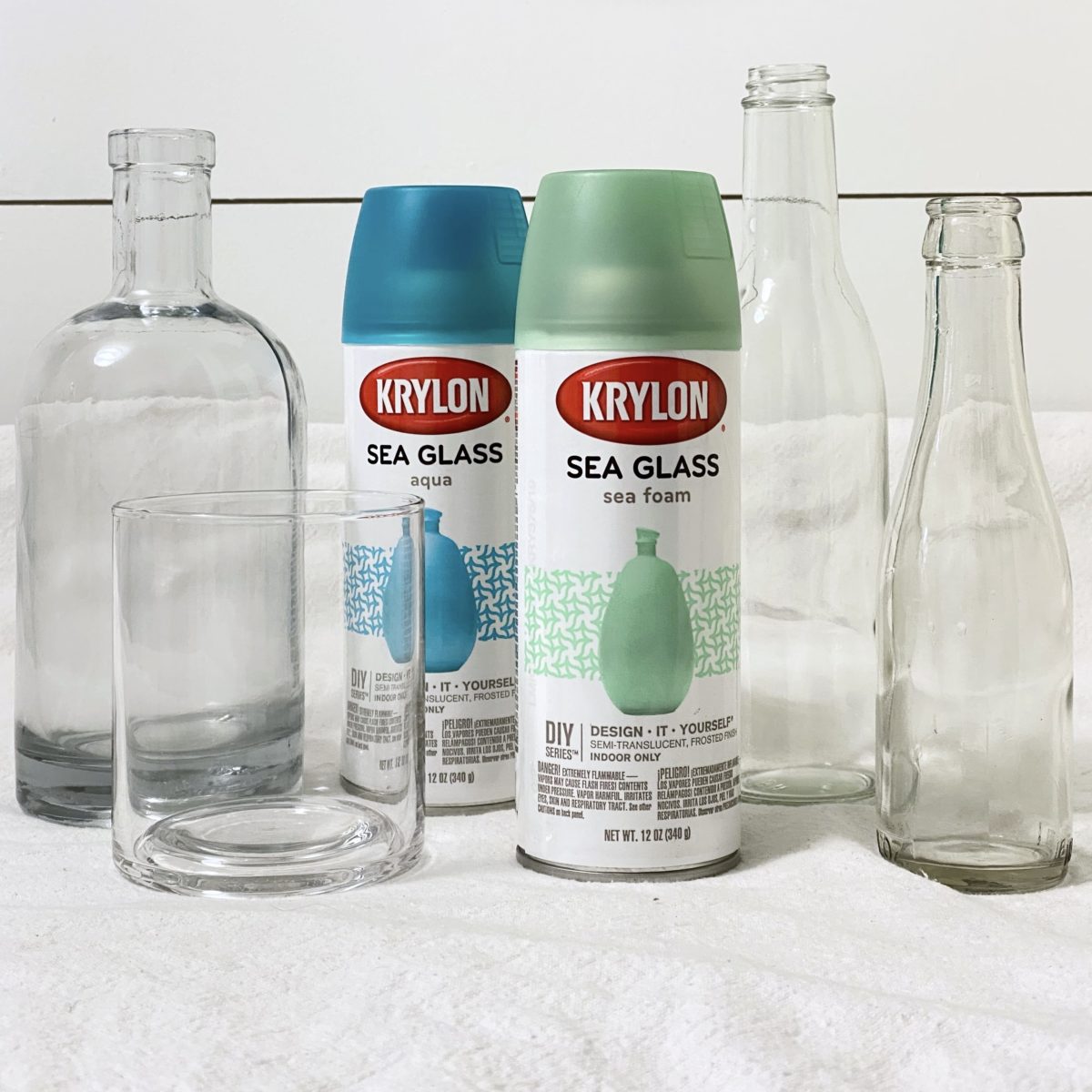 Glass bottles and sea glass spray paint to make DIY sea glass bottles.