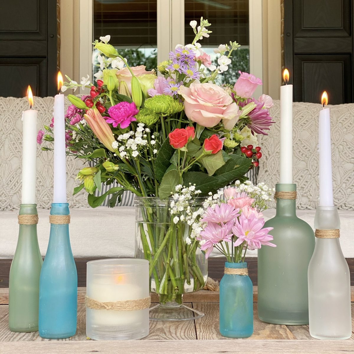 DIY sea glass bottles on the porch styled with flowers and candles.