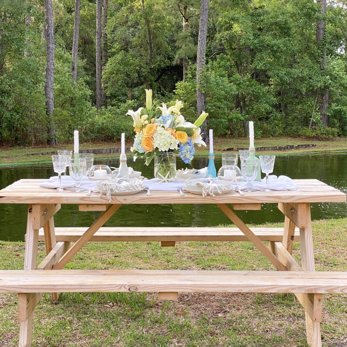Simple summer tablescape on a picnic table by a pond.