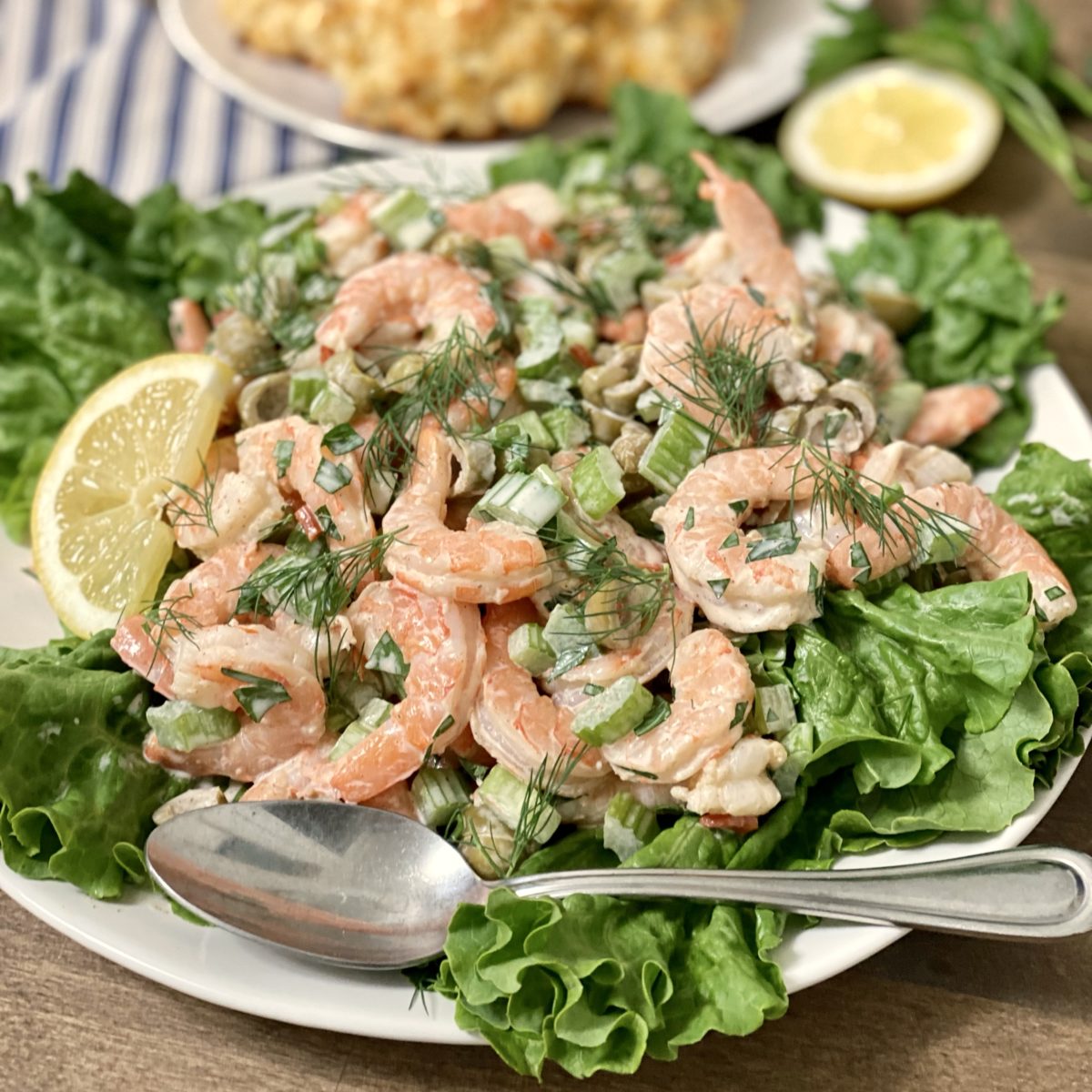 The best shrimp salad on a bed of lettuce with a lemon wedge.