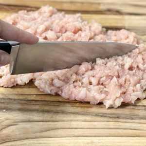 Finely chopping chicken breast for smash burgers.