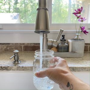 Filling a mason jar with water from the kitchen faucet.