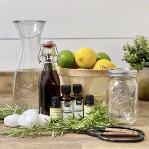 Supplies needed to make DIY mason jar luminaries for summer including water, lemons, limes, vanilla extract, rosemary, and floating tea candles.