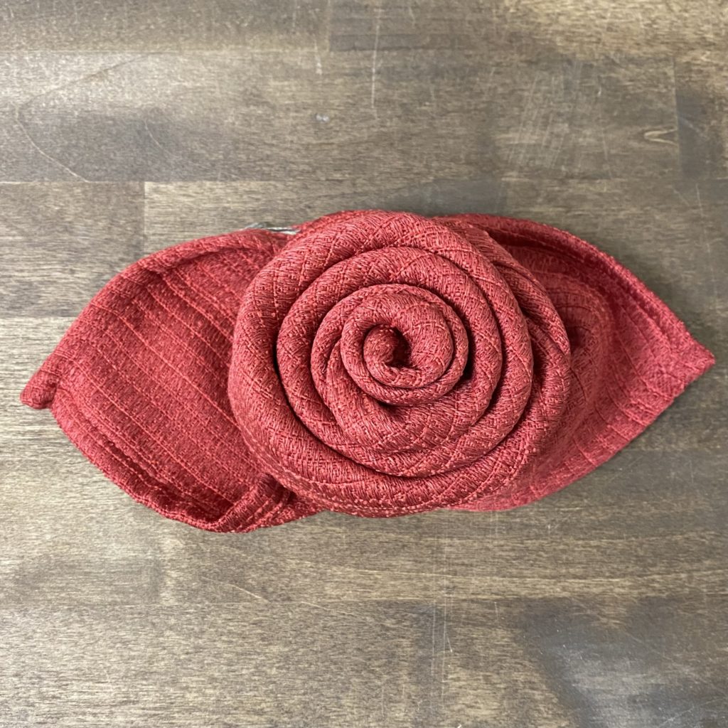 A red cloth napkin folded into a rose.