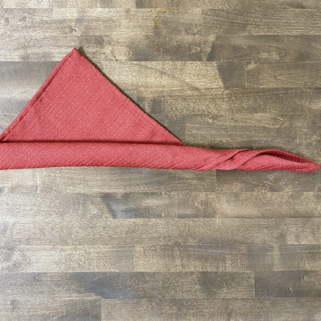 a red cloth napkin from the bottom of the triangle leaving a 4 to5-inch triangle at the top.