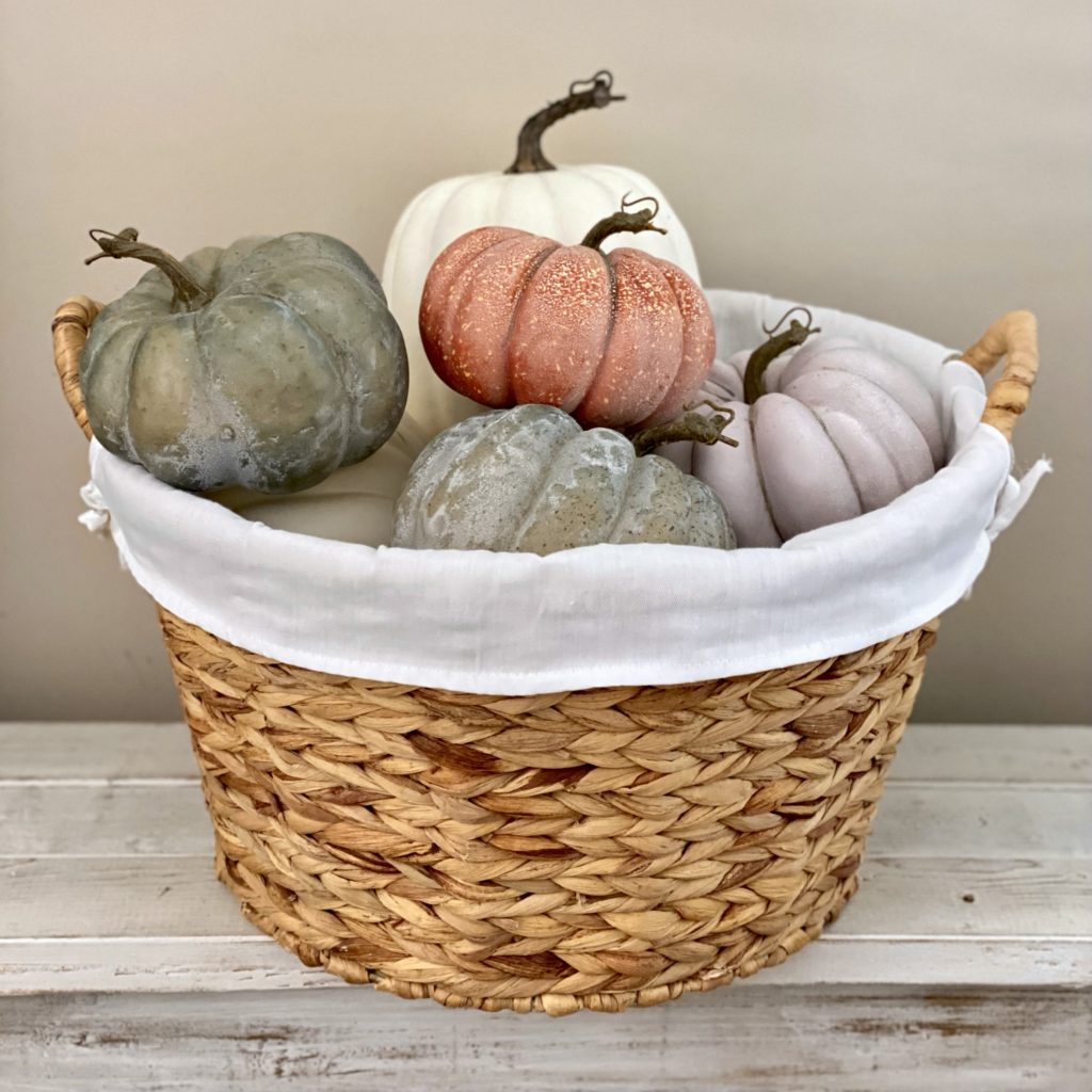 A basket filled with faux pumpkins.