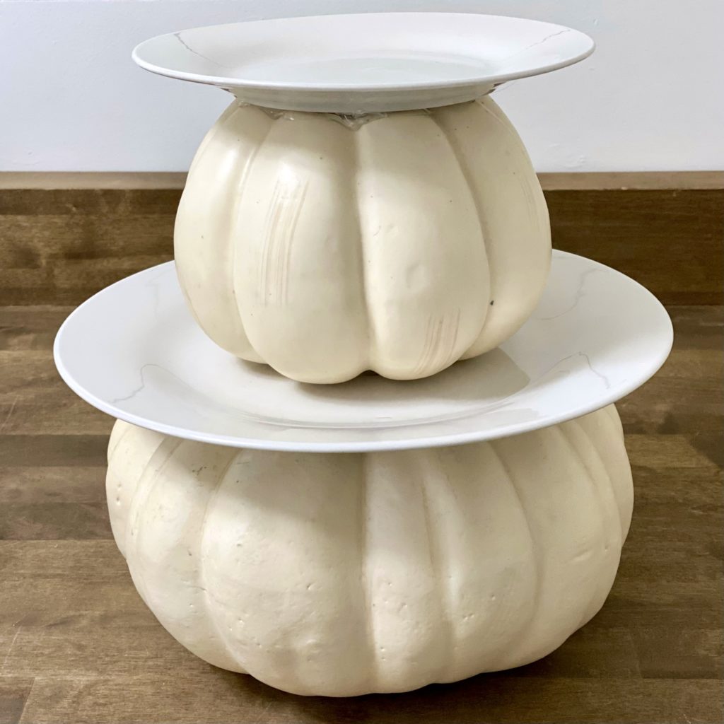 Two tiered DIY tray for fall with white faux pumpkins and plates stacked on top of one another.
