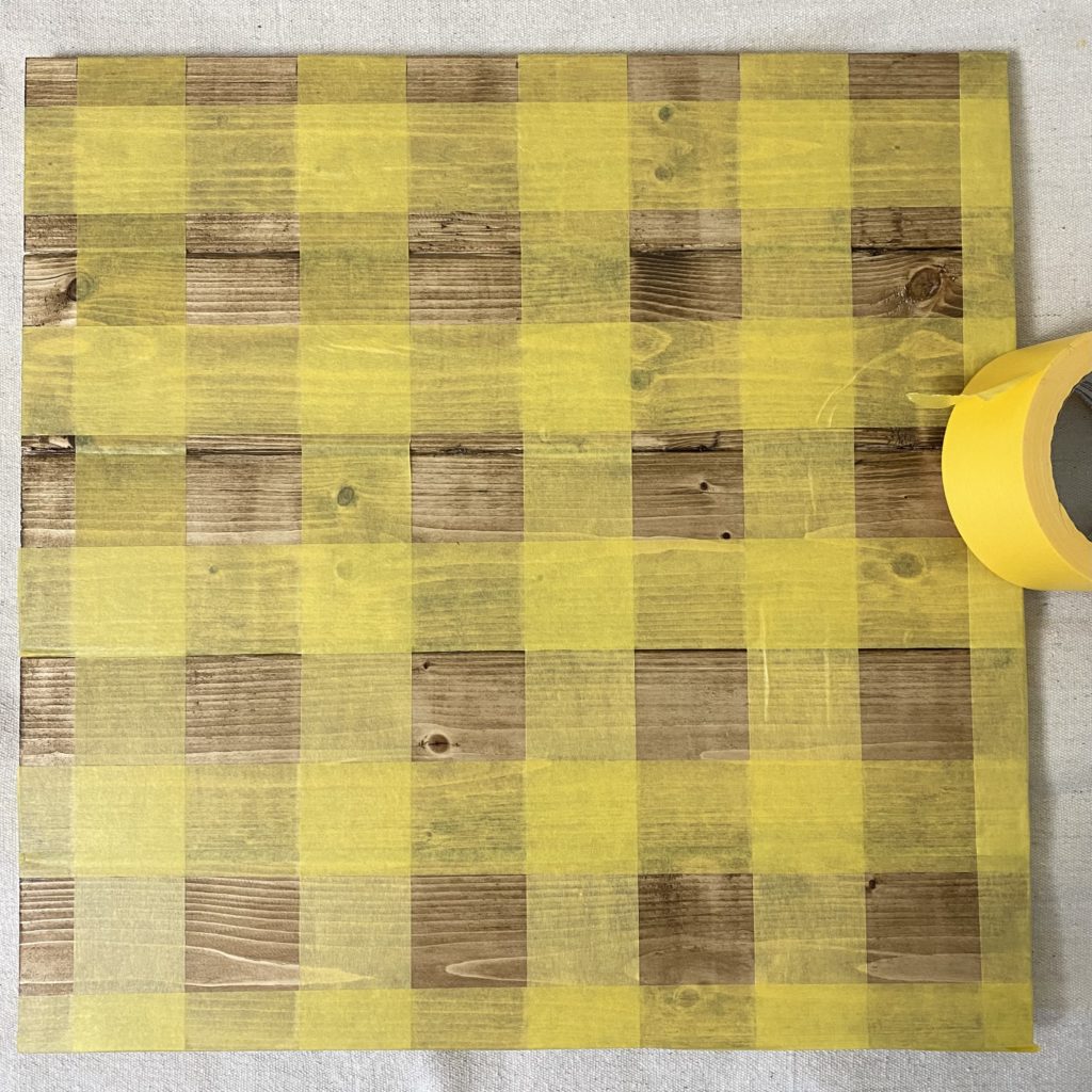 Tape stretched out across both sides of the board creating the first set of squares for the checker board.