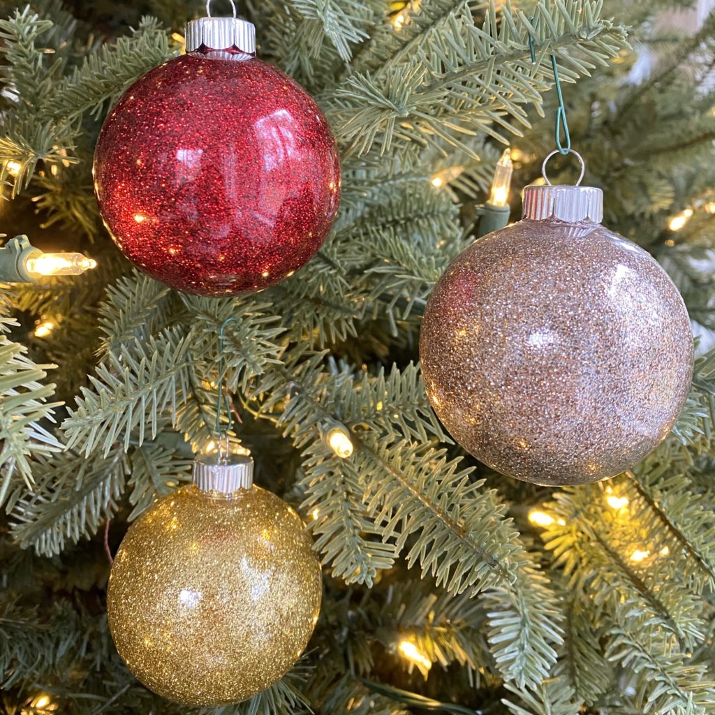 A red, gold, and champagne colored glitter ornament on the Christmas tree.