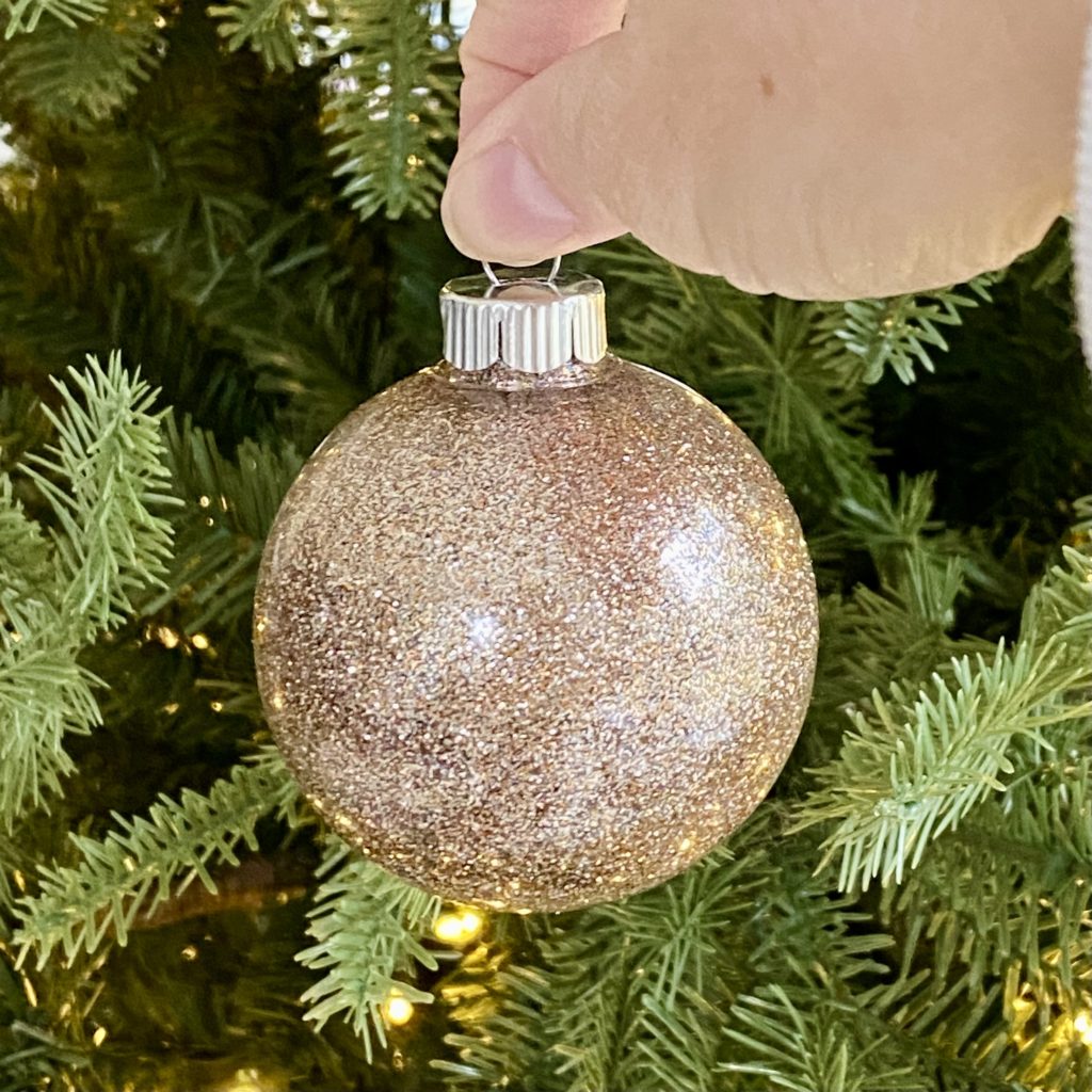 Hanging a beautiful glitter ornament on the Christmas tree.
