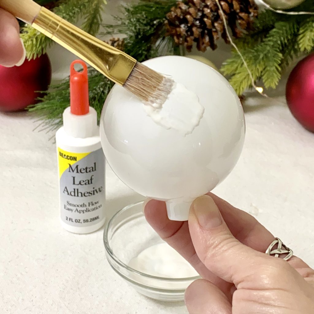 Applying the adhesive onto the ornament with a paintbrush.
