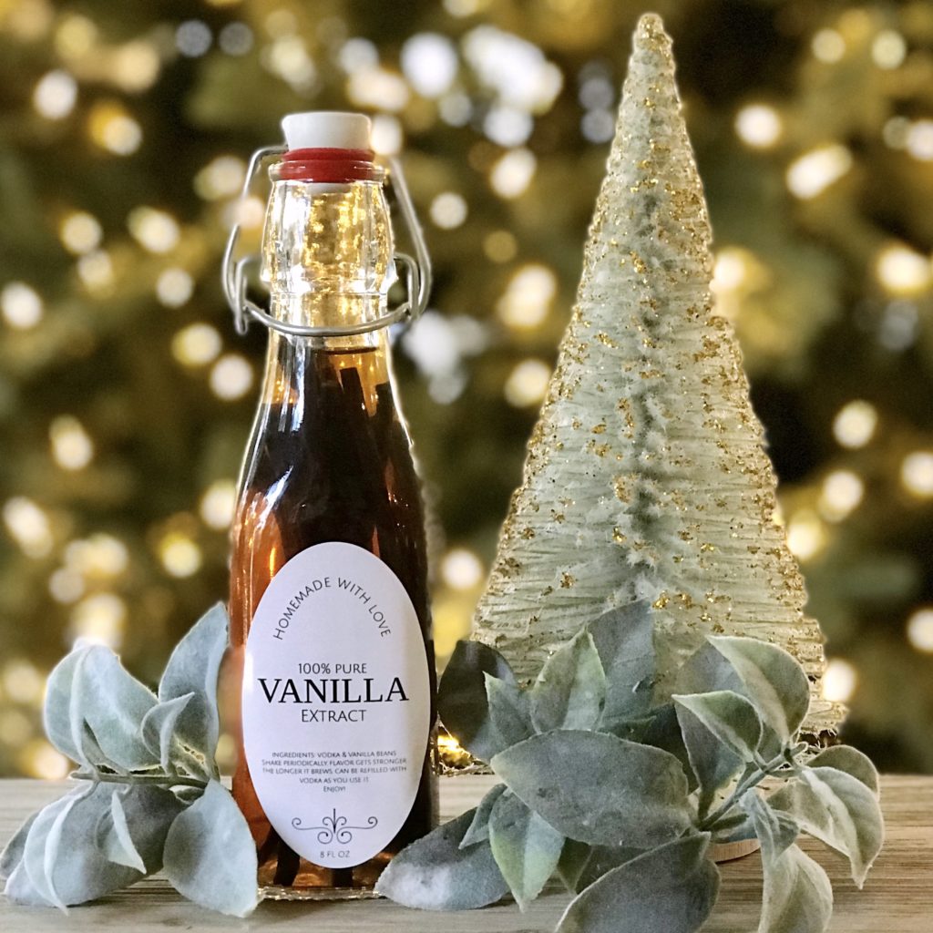 A bottle of homemade vanilla extract in front of a Christmas tree.
