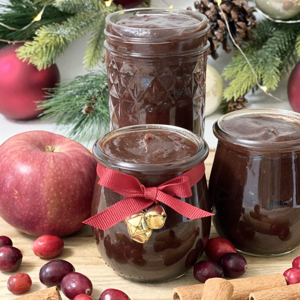 Holiday Cranberry Apple Butter in jars tied with a red bow and gold bells for decoration and gift giving.