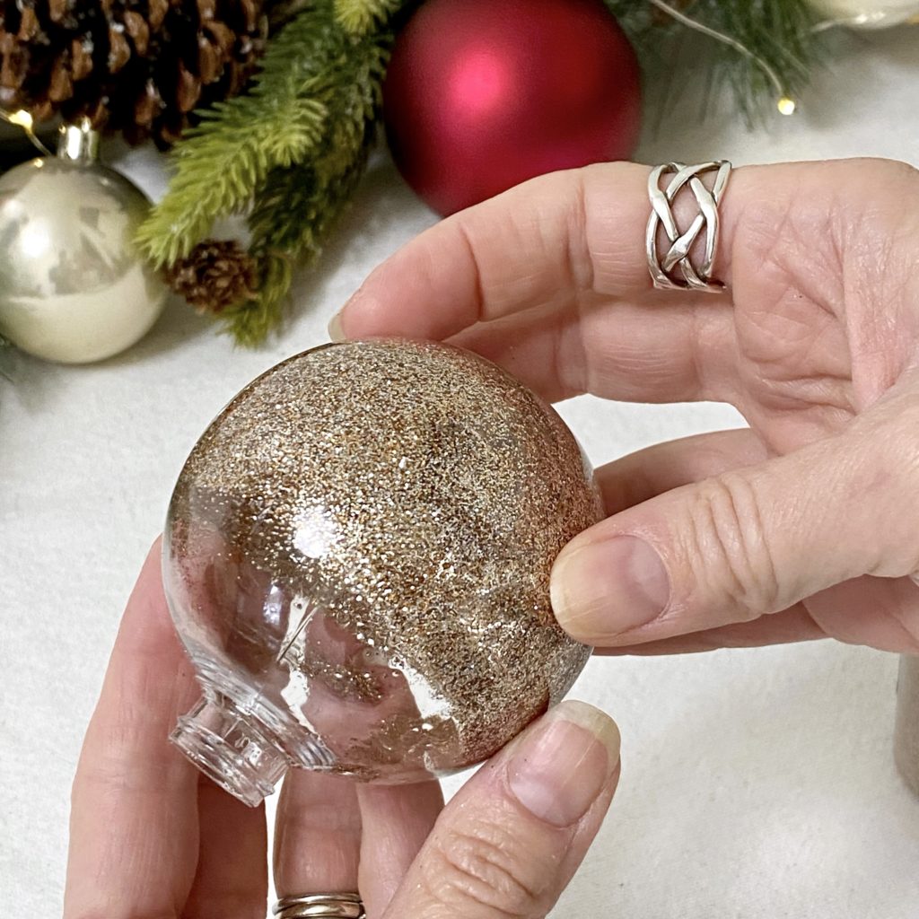 Extra fine glitter being swirled around a clear plastic ornament with wood oil in it.