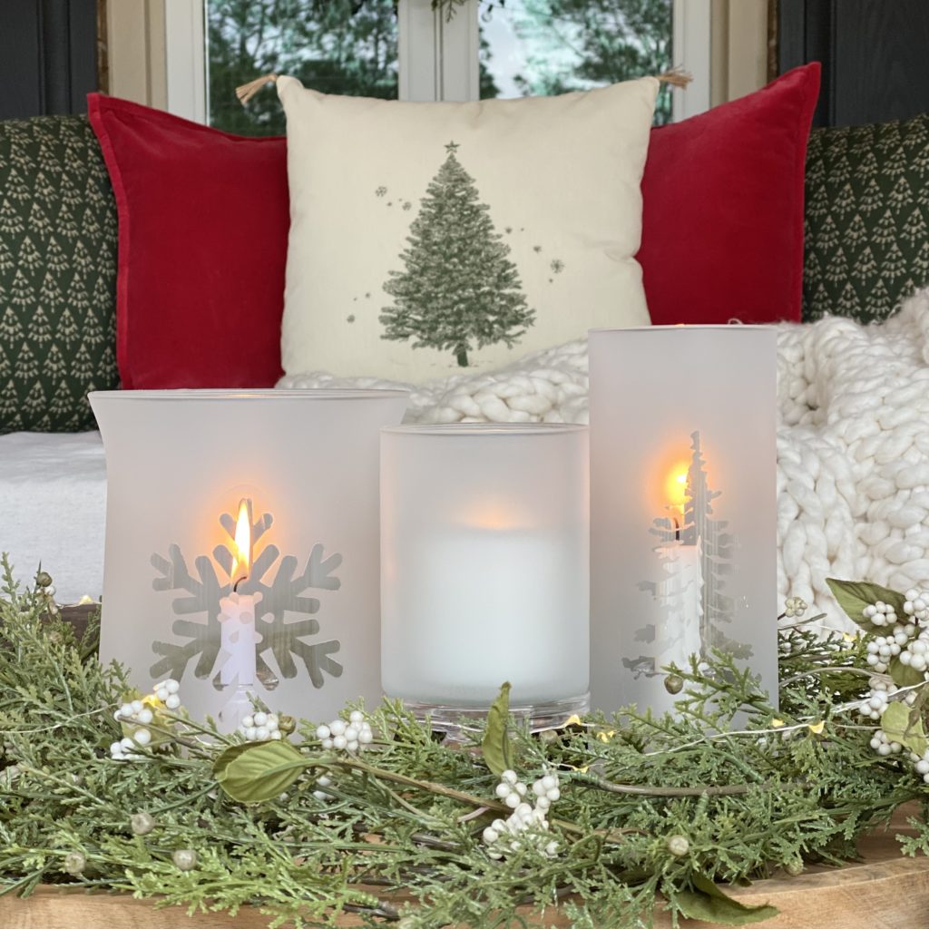 A close-up of Frosted Glass Winter Candle Holders styled on a tray with evergreens on the coffee table.