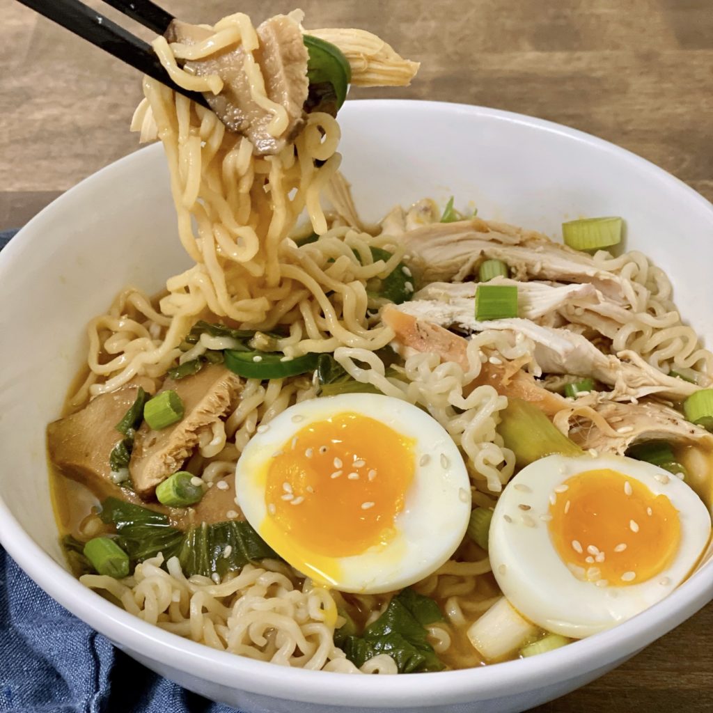 Eating easy weeknight chicken ramen out of a white bowl with chopsticks.