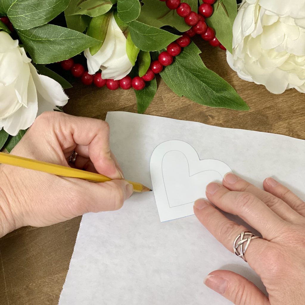 Tracing a heart onto freezer paper with a pencil.