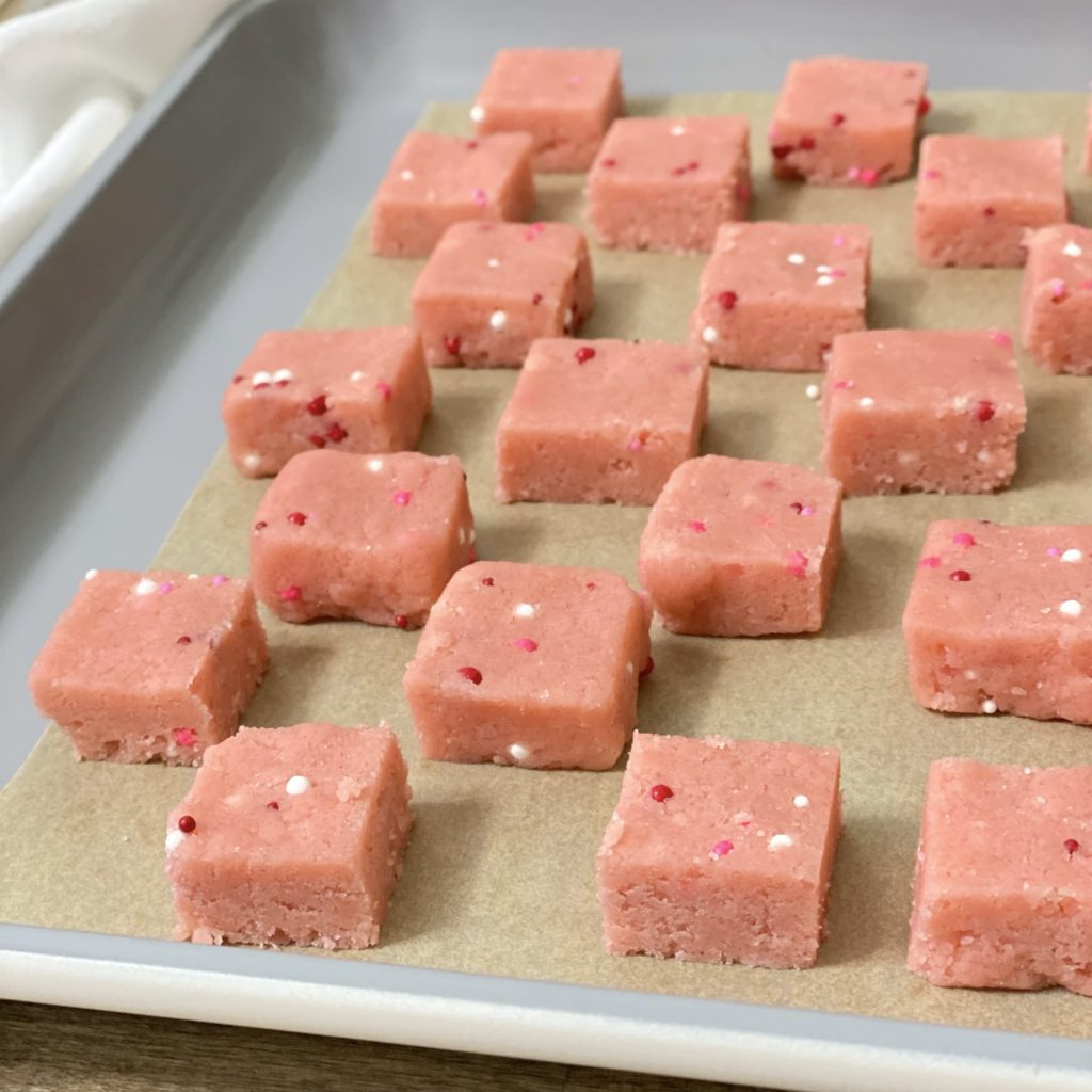 Sweet Valentine shortbread bites cutout in small cubes on a cookie sheet ready to bake in the oven.