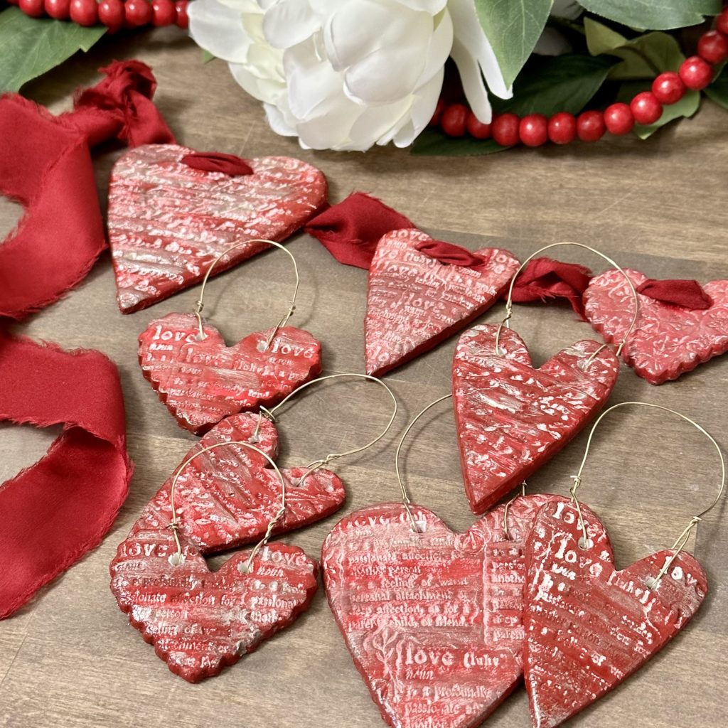 Clay heart Valentine’s decorations strung on red ribbon and with gold wire on them to hang them.