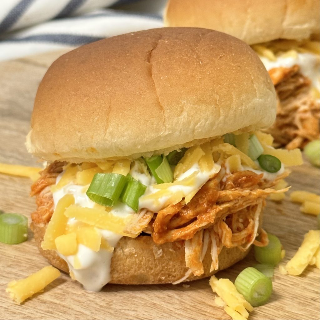 Close up of a slow cooker buffalo chicken slider with all the toppings.