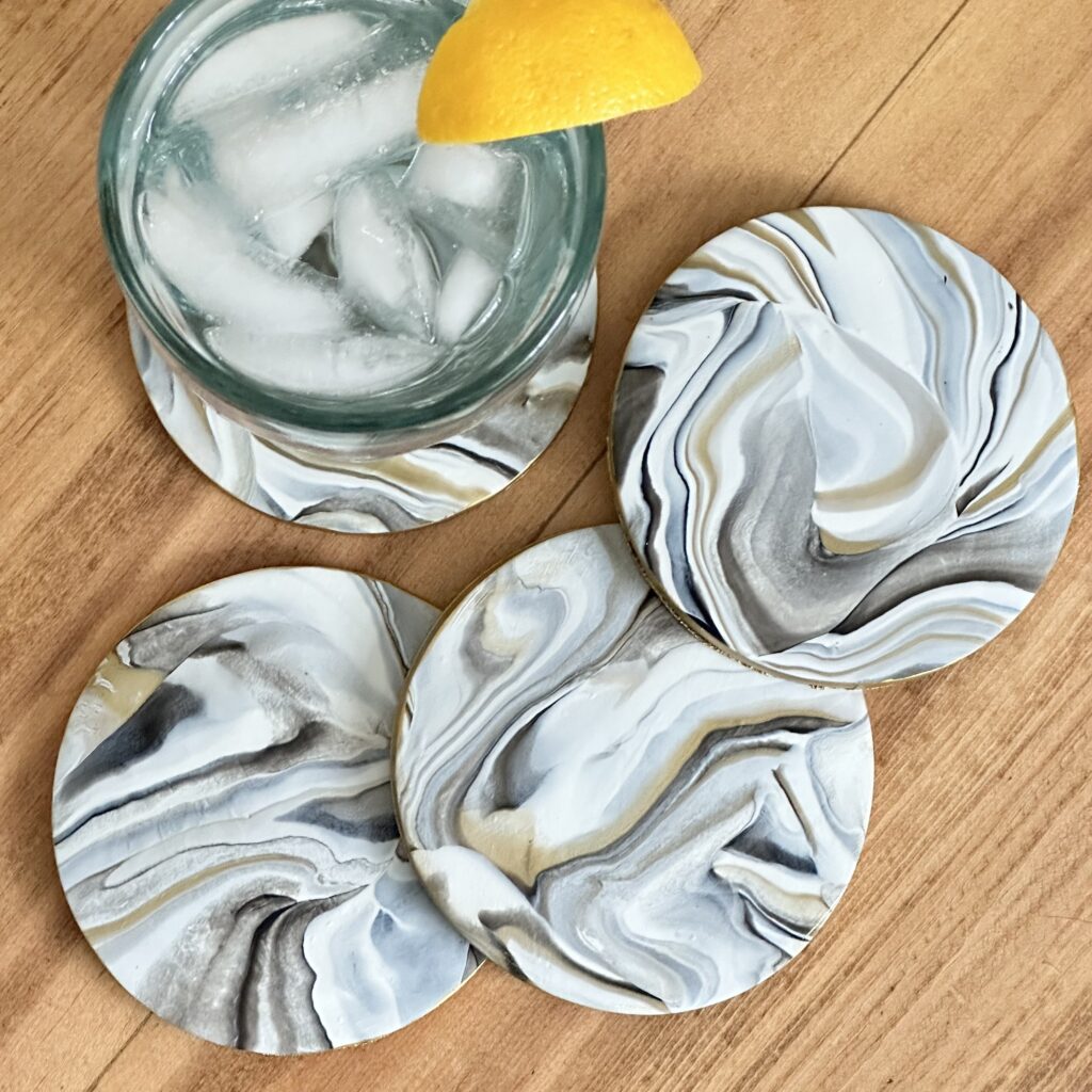 Marbleized Polymer Clay Coasters On a table with a glass of lemon water on one of them.