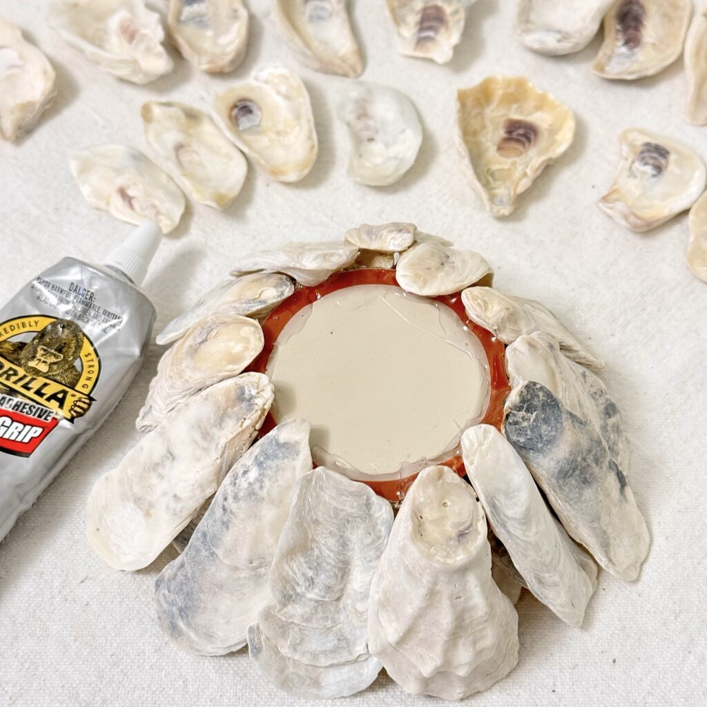 Attaching the medium size oyster shells to the lid with adhesive.