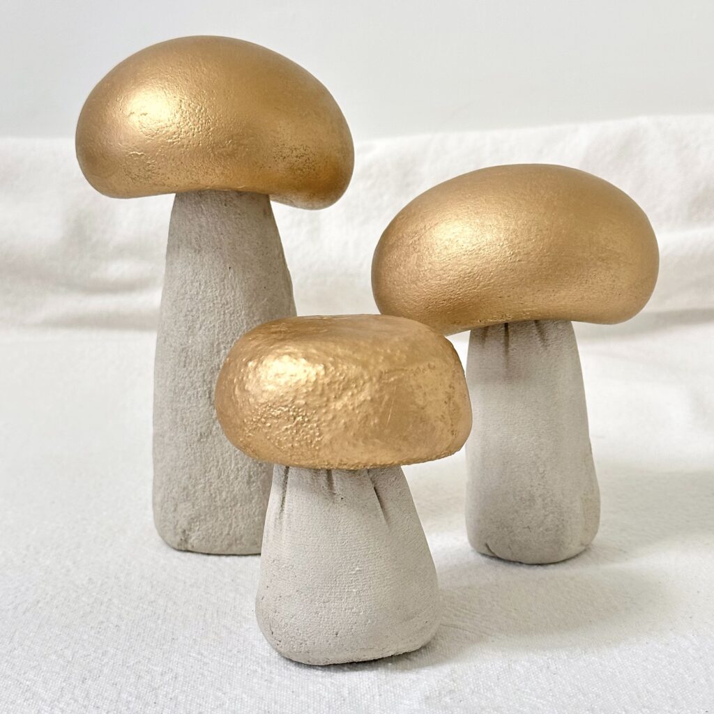 Three concrete mushrooms all finished with gold painted caps.