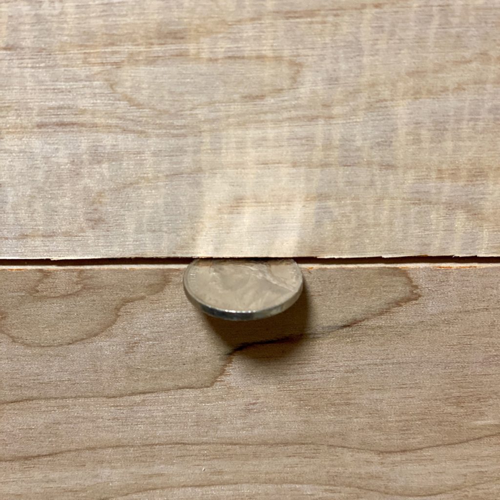 Nickel in between wood planks on the wall.