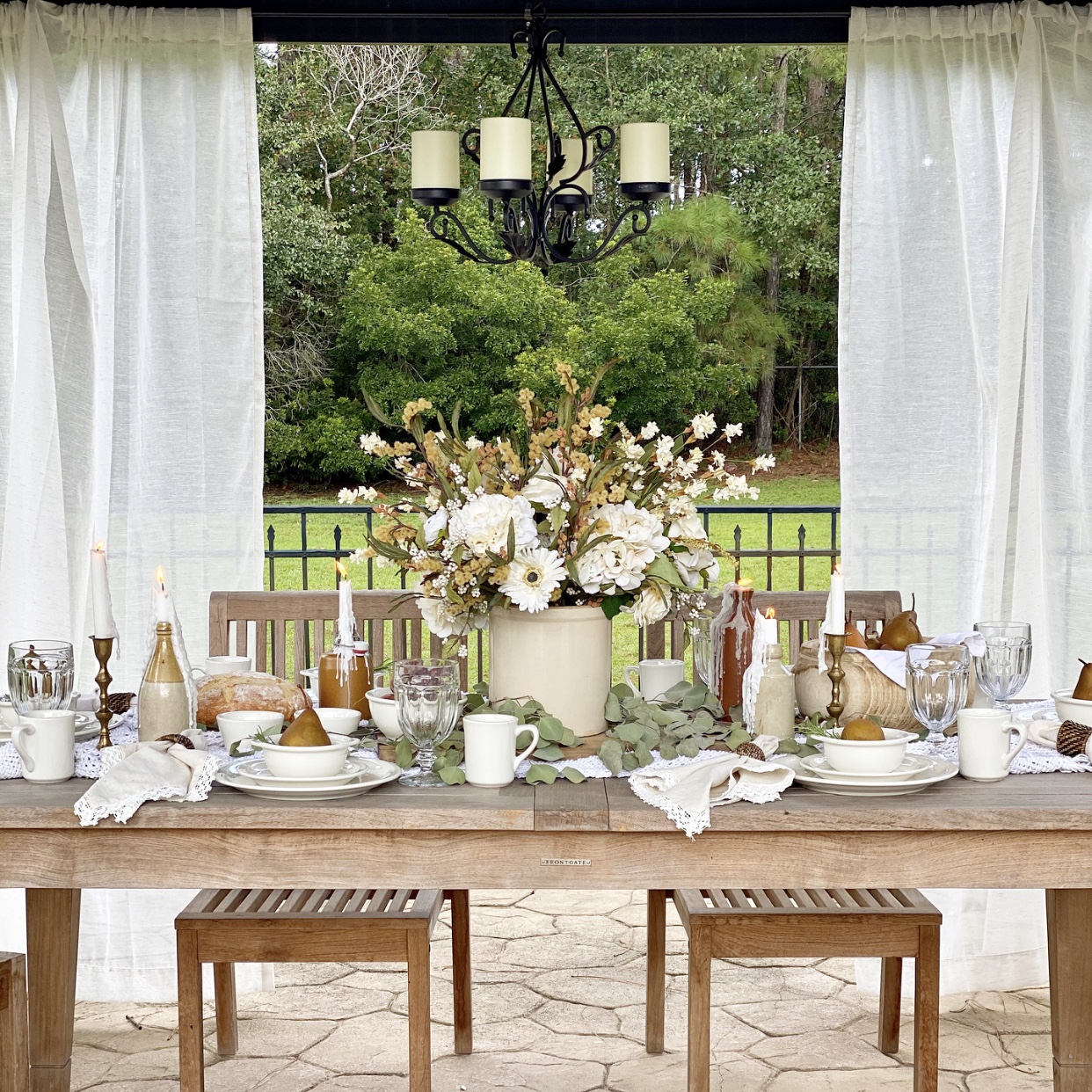 Outdoor tablescape with white dishes, a fall arrangement, and pears. 