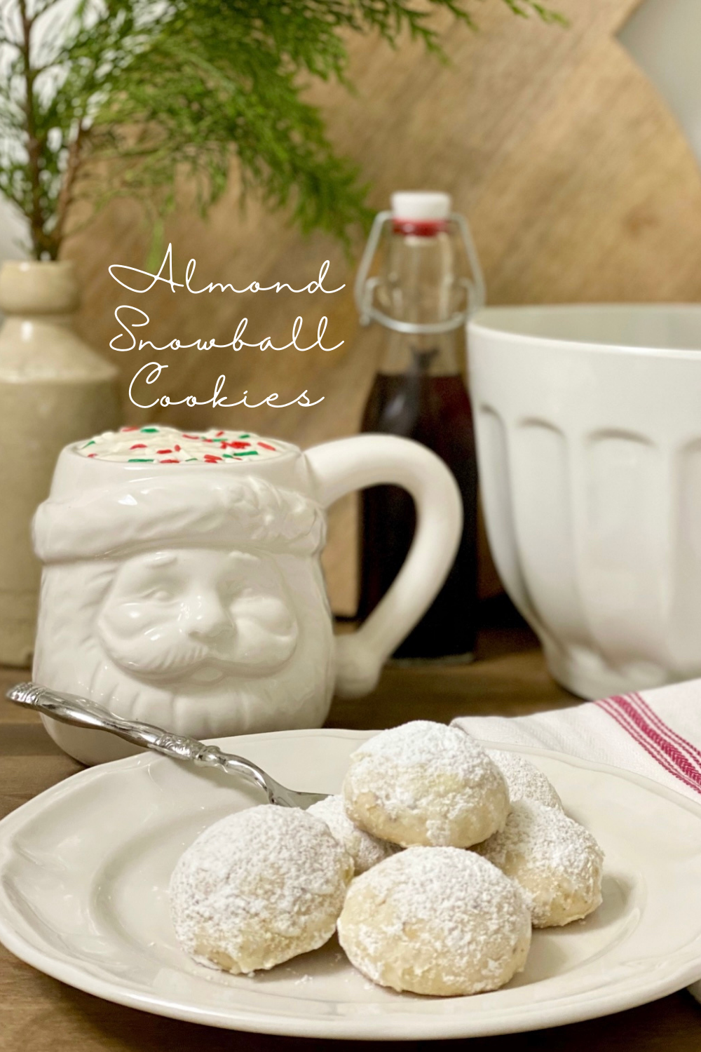 Plate of Almond Snowball Cookies with a Santa mug next to it.