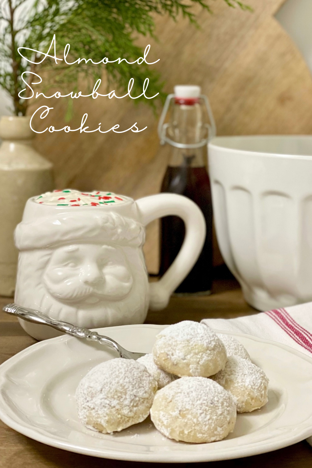 Plate of Almond Snowball Cookies with a Santa mug next to it.