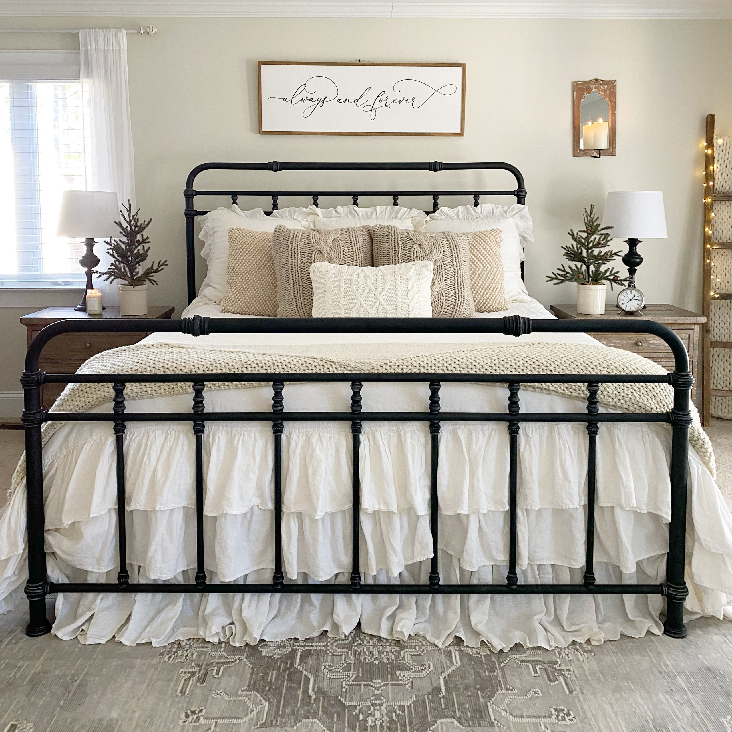 Black iron bed with white and beige bedding and pillows.